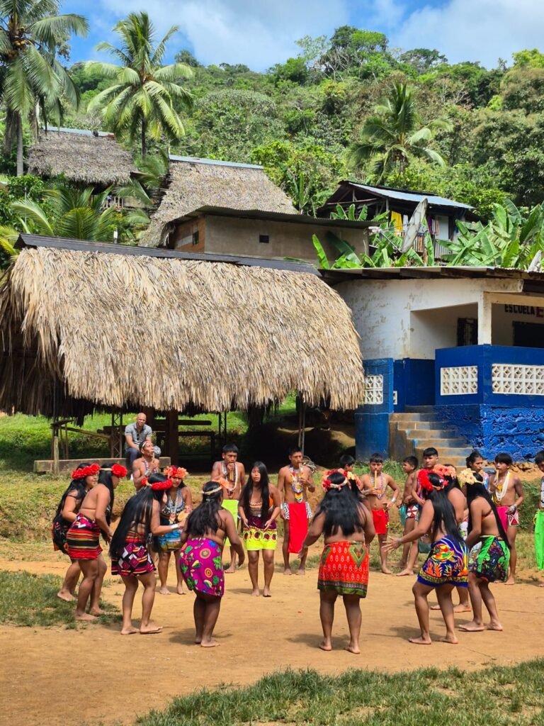 Emberá community in traditional dress performing a welcome dance among thatched-roof houses in their village on the Chagres