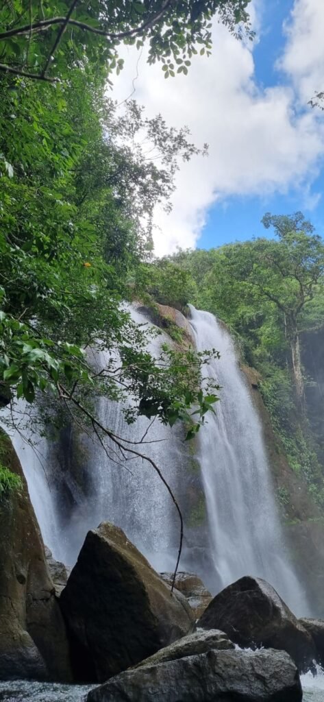Twin waterfall cascading down a cliff into the Panama rainforest under a blue sky