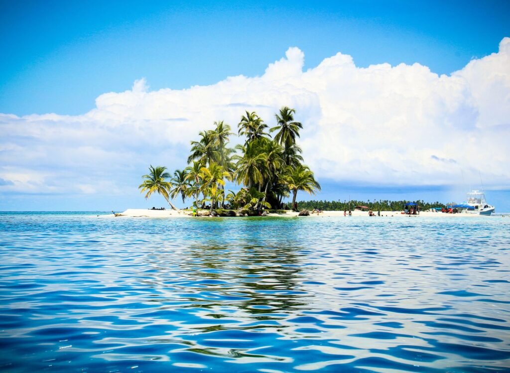 Palm trees leaning over a white-sand beach with clear turquoise water in Guna Yala, Panama