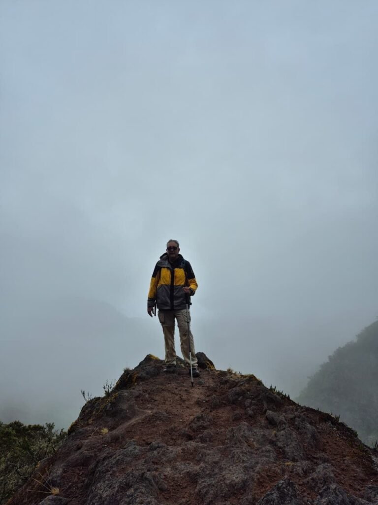 Hiker standing on a rocky summit shrouded in cloud forest fog in the Chiriqui highlands near Boquete